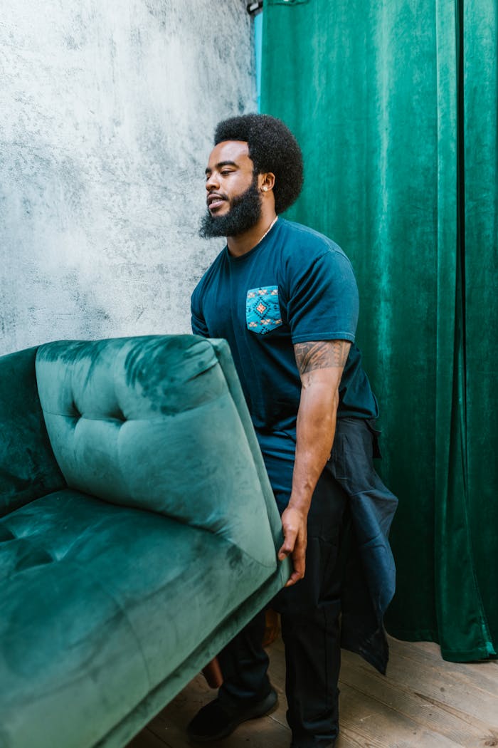 A Bearded Man Carrying a Green Couch